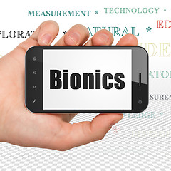 Image showing Science concept: Hand Holding Smartphone with Bionics on display