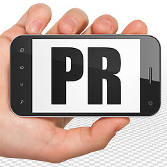 Image showing Marketing concept: Hand Holding Smartphone with PR on display