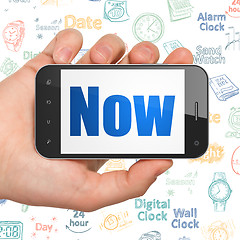 Image showing Time concept: Hand Holding Smartphone with Now on display