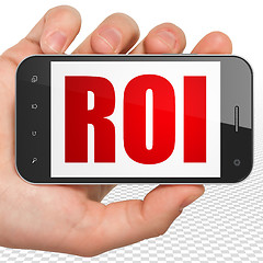 Image showing Finance concept: Hand Holding Smartphone with ROI on display