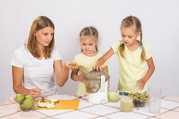 Image showing Mom teaches children to squeeze the juice in a juicer