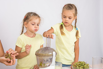 Image showing The girl ate a slice of pear is another girl squeezes out juice