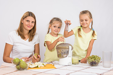 Image showing Happy family prepares freshly squeezed juice in a juicer