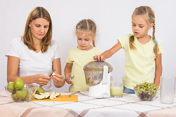 Image showing Mom cut pear juice, the children throw them in a juicer