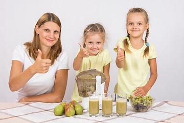 Image showing Mother and two daughters show a thumbs up by preparing freshly squeezed juice