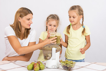 Image showing Mother and two daughters knocked against each other with glasses of freshly made juice from the pears and grapes