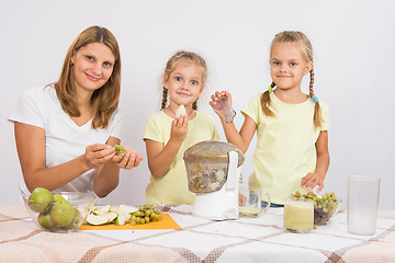 Image showing Mother and daughter squeezing juice from pears and grapes