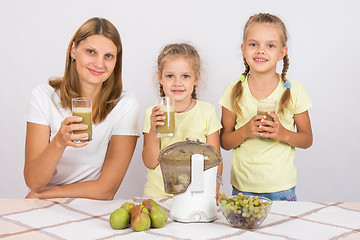 Image showing Mother and two daughters with glasses of freshly made juice from the pears and grapes