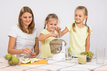 Image showing Happy family squeezes juice in a juicer