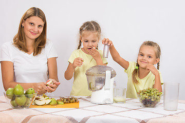 Image showing Girl gnaws pears until mom and sister squeezed juice in a juicer