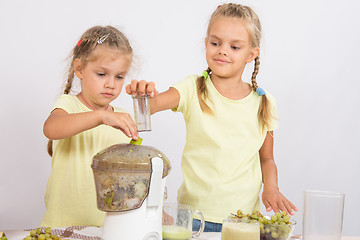 Image showing Two girls squeezed juice in a juicer