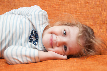 Image showing The three-year cheerful girl lying on the sofa