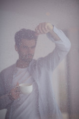 Image showing relaxed young man drink first morning coffee withh rain drops on