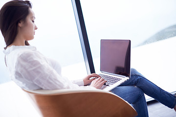 Image showing relaxed young woman at home working on laptop computer