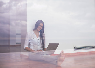 Image showing relaxed young woman at home working on laptop computer