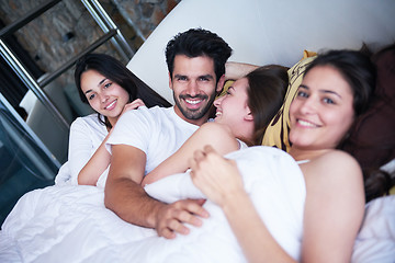 Image showing handsome man in bed with three beautiful woman