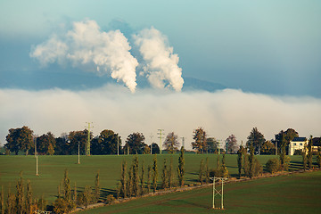 Image showing smoking chimneys in from factory hidden in mist