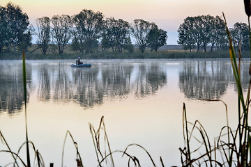 Image showing A fisherman in a boat sailing in the morning mist