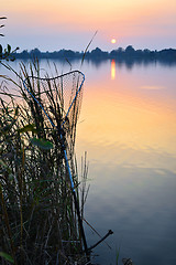 Image showing Fishing rod and tank against the sunset on the lake fishing