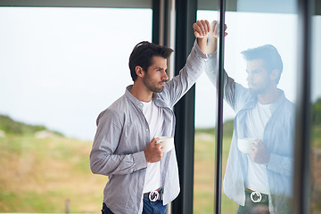 Image showing relaxed young man drink first morning coffee withh rain drops on