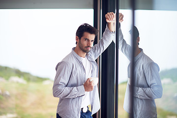 Image showing relaxed young man drink first morning coffee withh rain drops on