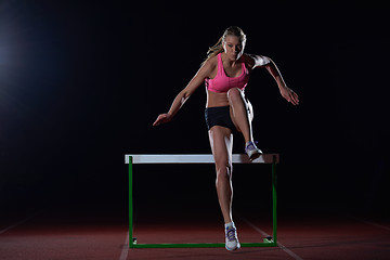 Image showing woman athlete jumping over a hurdles