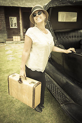 Image showing Happy 1920s Dressed Girl Holding Suitcase Next to Vintage Car