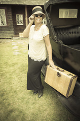 Image showing Happy 1920s Dressed Girl Holding Suitcase Next to Vintage Car
