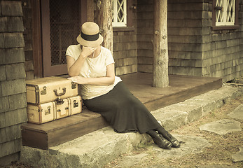 Image showing Distressed 1920s Girl Near Suitcases on Porch with Vintage Effec