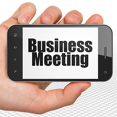 Image showing Business concept: Hand Holding Smartphone with Business Meeting on display