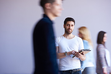 Image showing student working on tablet, people group passing by