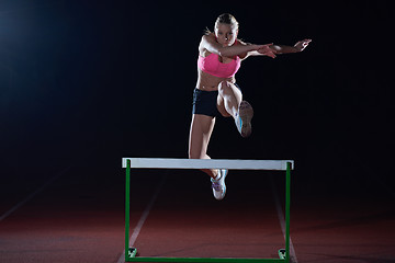 Image showing woman athlete jumping over a hurdles