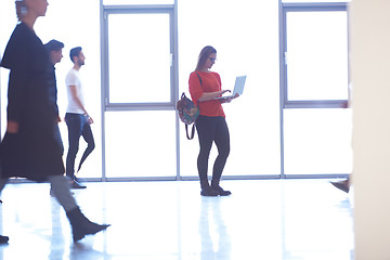 Image showing student girl standing with laptop, people group passing by