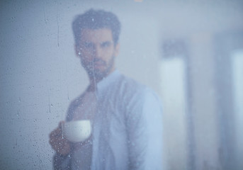 Image showing relaxed young man drink first morning coffee withh rain drops on