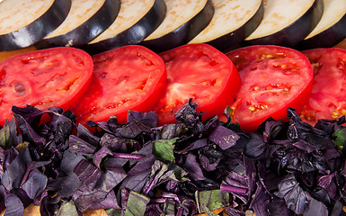 Image showing Sliced eggplant tomato and basil leaves horizontally