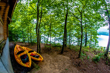 Image showing two orange kayaks standing near cabin by the lake