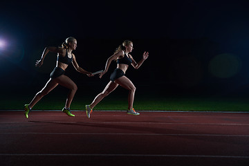 Image showing athletic runners passing baton in relay race