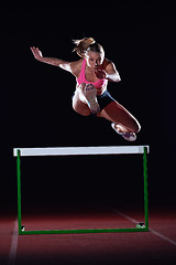 Image showing woman athlete jumping over a hurdles