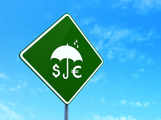 Image showing Protection concept: Money And Umbrella on road sign background