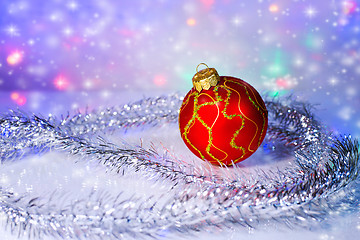 Image showing Red Christmas-tree ball and tinsel. Christmas decorations.