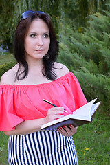 Image showing Brunette writing in diary in the park
