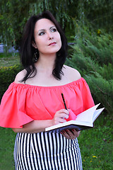 Image showing Brunette writing in diary in the park