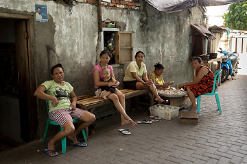 Image showing Indonesian woman peel garlic in Manado shantytown