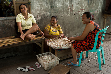 Image showing Indonesian woman peel garlic in Manado shantytown