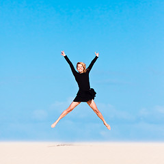 Image showing Girl jumping in the air on sand dune.