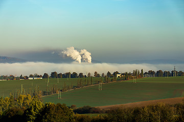 Image showing smoking chimneys in from factory hidden in mist