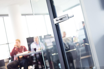 Image showing Trough glass door view of corporate meeting.