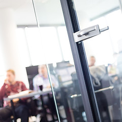 Image showing Trough glass door view of corporate meeting.