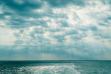 Image showing Clouds over the ocean with sunbeams