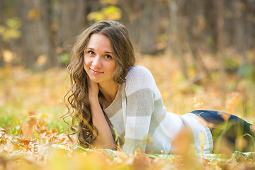 Image showing Young beautiful girl lies on the Scourge in the yellow fallen leaves